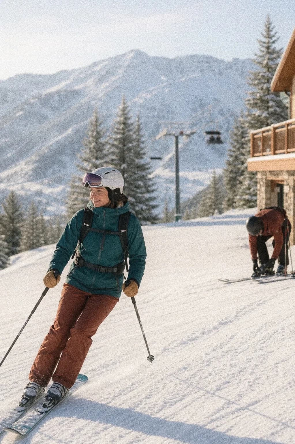 Skier crossing a snowy mountain slope near a lodge.